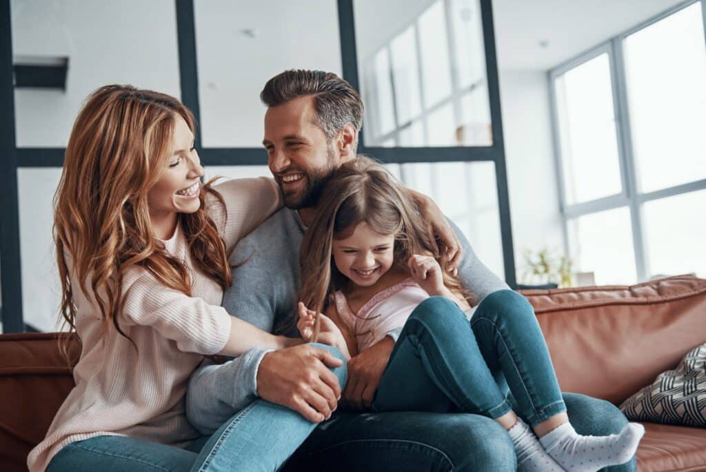 Happy young family smiling and embracing while bonding together at home